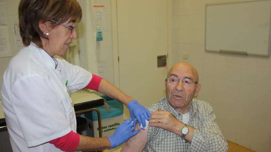 Una metgessa posa la vacuna de la grip a un home