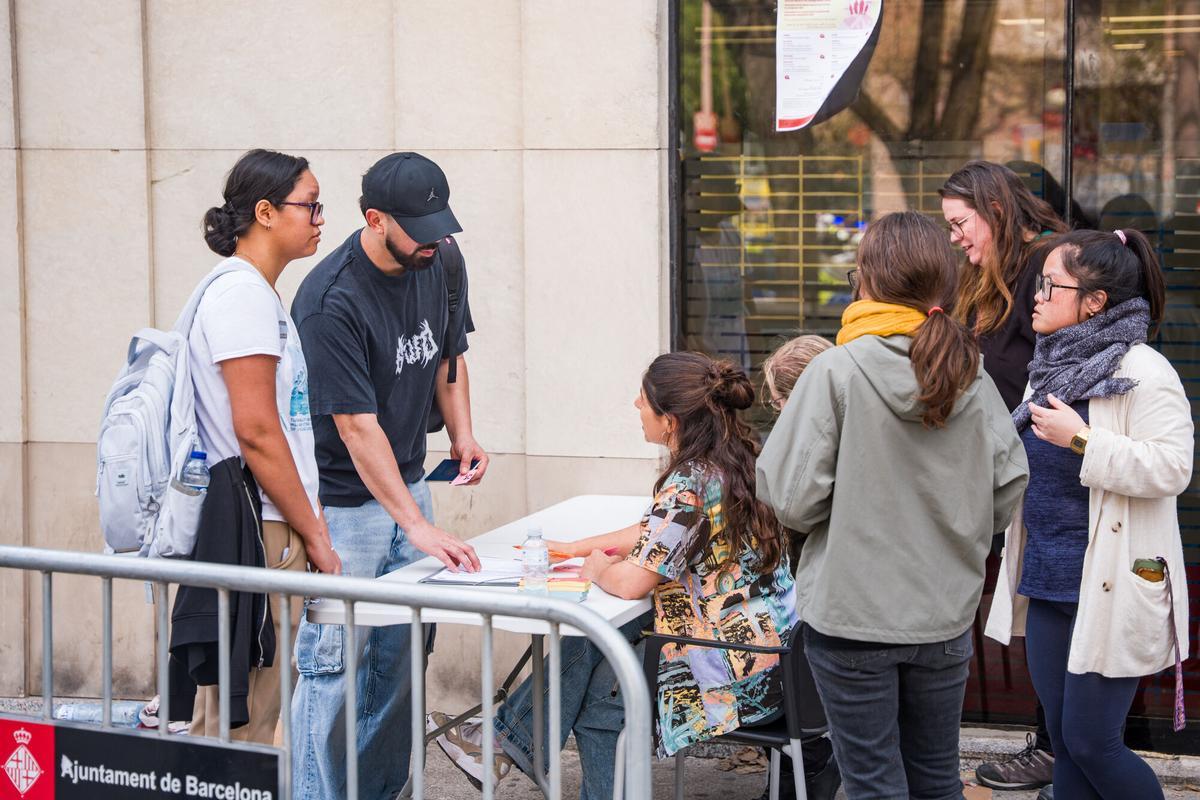 Caos y una larga cola de personas que esperan regularizar su situación en España en la Oficina de Benestar Social i Família de Barcelona-Sants/Eixample.