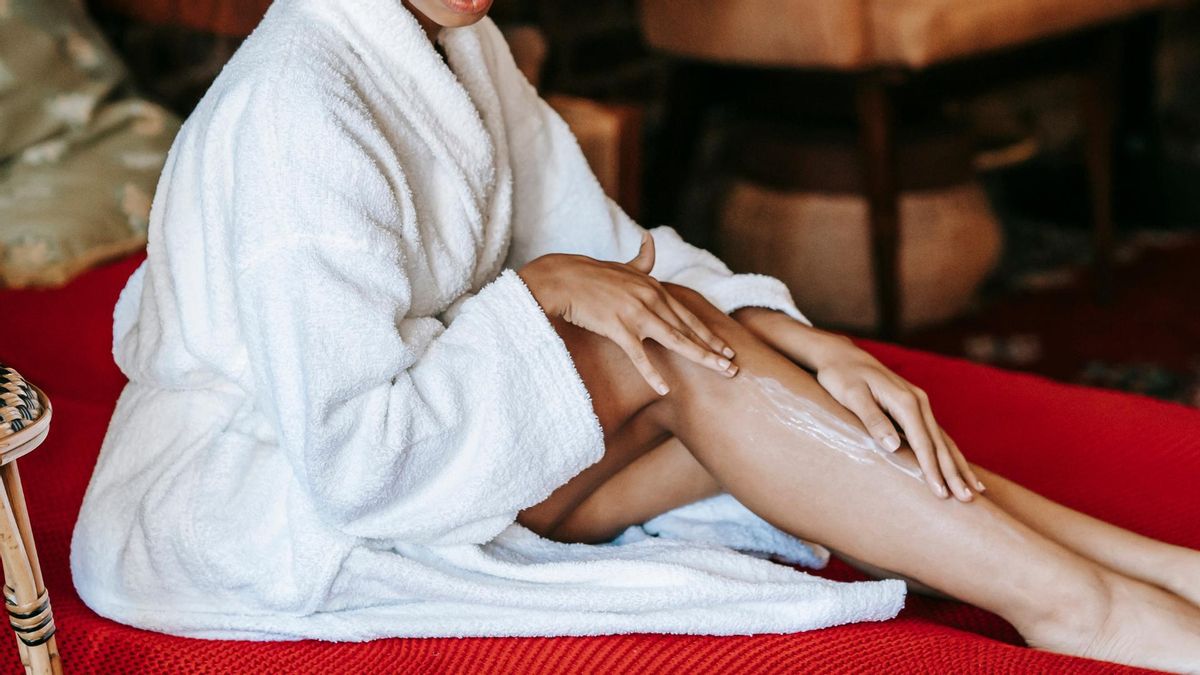 Una mujer se extiende una crema en las piernas.