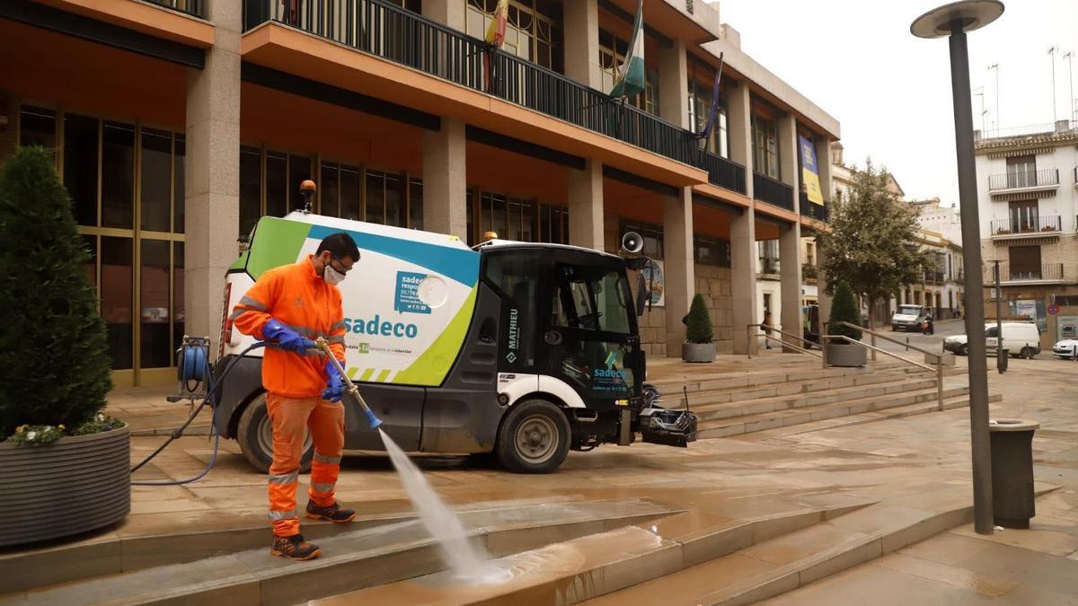 Un operario de Sadeco limpia los efectos de la calima a las puertas del Ayuntamiento.