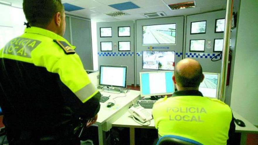 Dos agentes policiales observan la circulación rodada en las calles avilesinas desde el centro de control de tráfico.