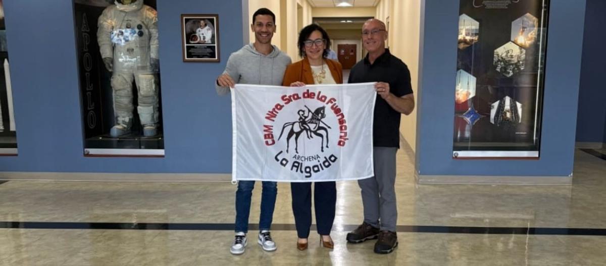 Jarrod Bales, Hamilton Fernández y Notlim, miembros de la NASA, sostienen la bandera enviada por el CBM Nuestra Señora de la Fuensanta de La Algaida. | L.O.
