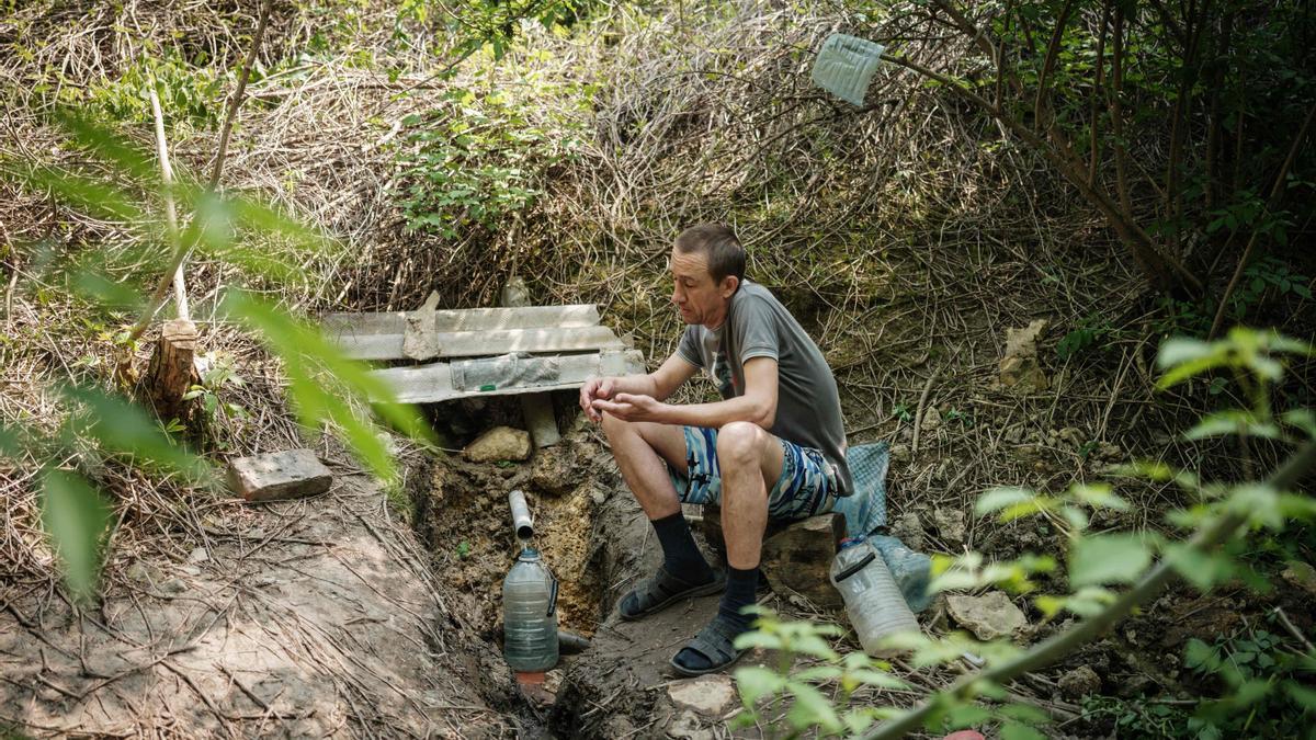 Un hombre recoge agua de una fuente natural en un bosque de Lisichansk utilizada por los locales durante generaciones, incluso durante la Segunda Guerra Mundial, después de que se cortara el suministro hídrico a causa de los bombardeos.