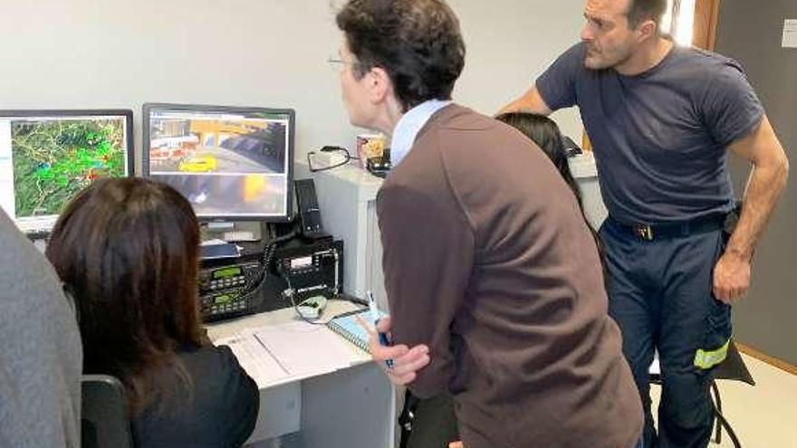 Un miembro del cuerpo de bomberos, a la derecha, dando indicaciones a dos teleoperadoras de Seguridad Ciudadana.