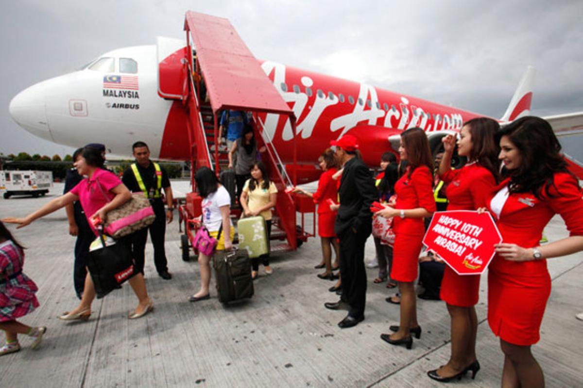 La tripulació d’un vol d’AirAsia rep festivament els passatgers en la celebració del desè aniversari de la companyia aèria ’low cost’, a Kuala Lumpur (Malàisia).