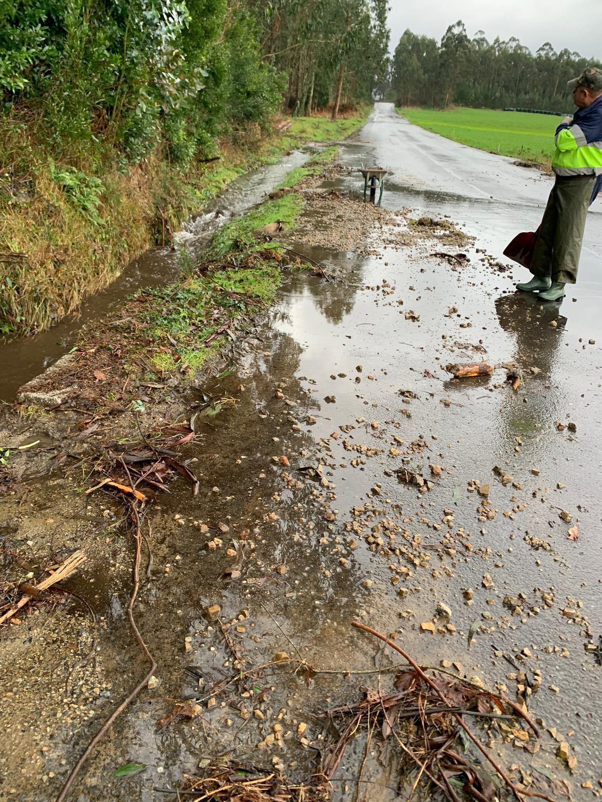 Operarios de Zas limpiando una vía local afectada por el arrastre de lodo y piedras.