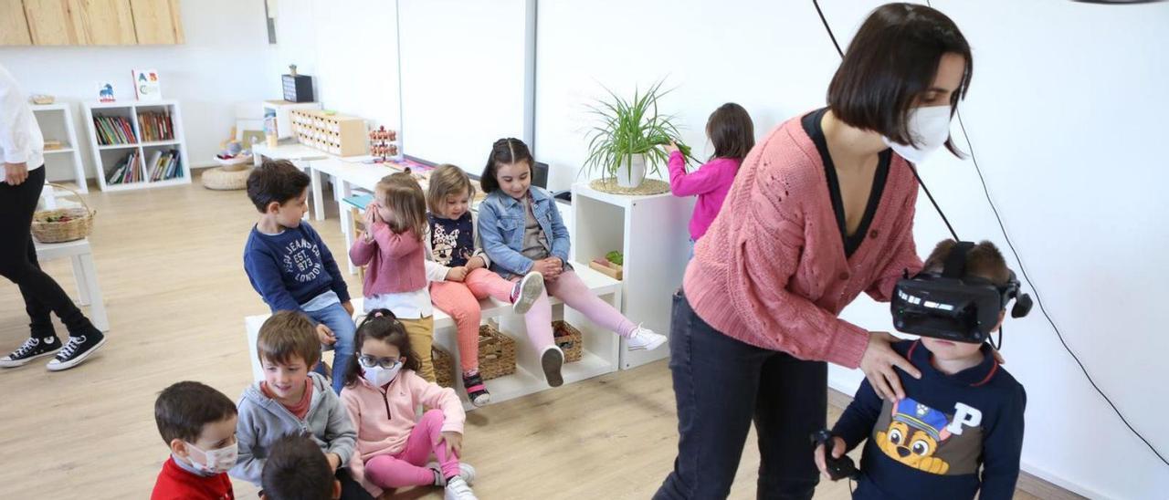 Alba Cacheda coloca las gafas de realidad virtual a un niño de la escuela de Donramiro.