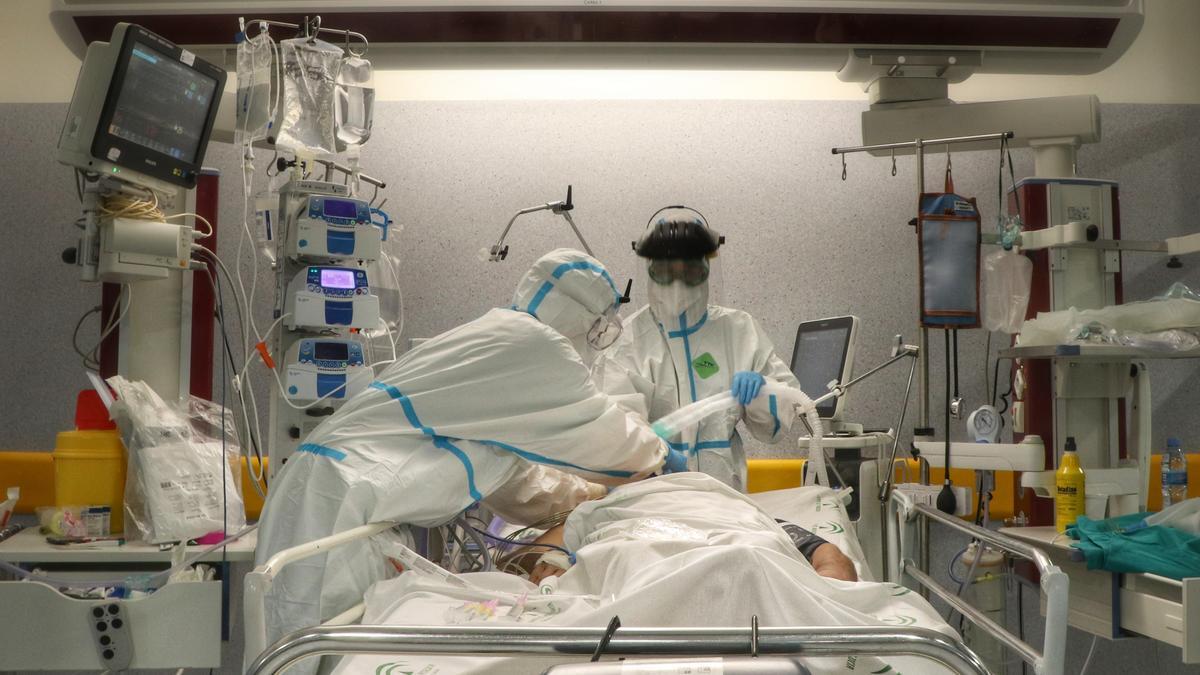 Dos sanitarios atienden a un paciente en una uci hospitalaria.