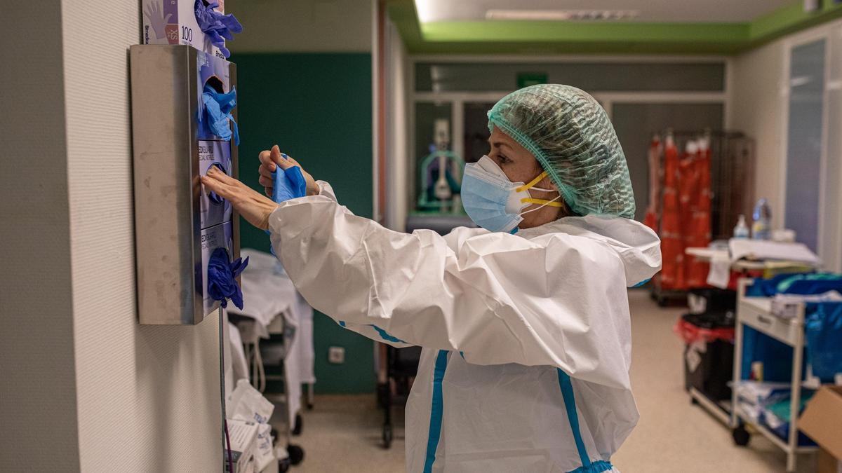 Una trabajadora de la UCI extrae los guantes del dispensador.