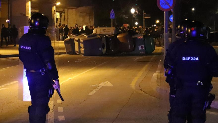 Una barricada al passeig de Canalejas de Girona amb la línia de Mossos d&#039;Esquadra en primer terme el 19 de febrer de 2021