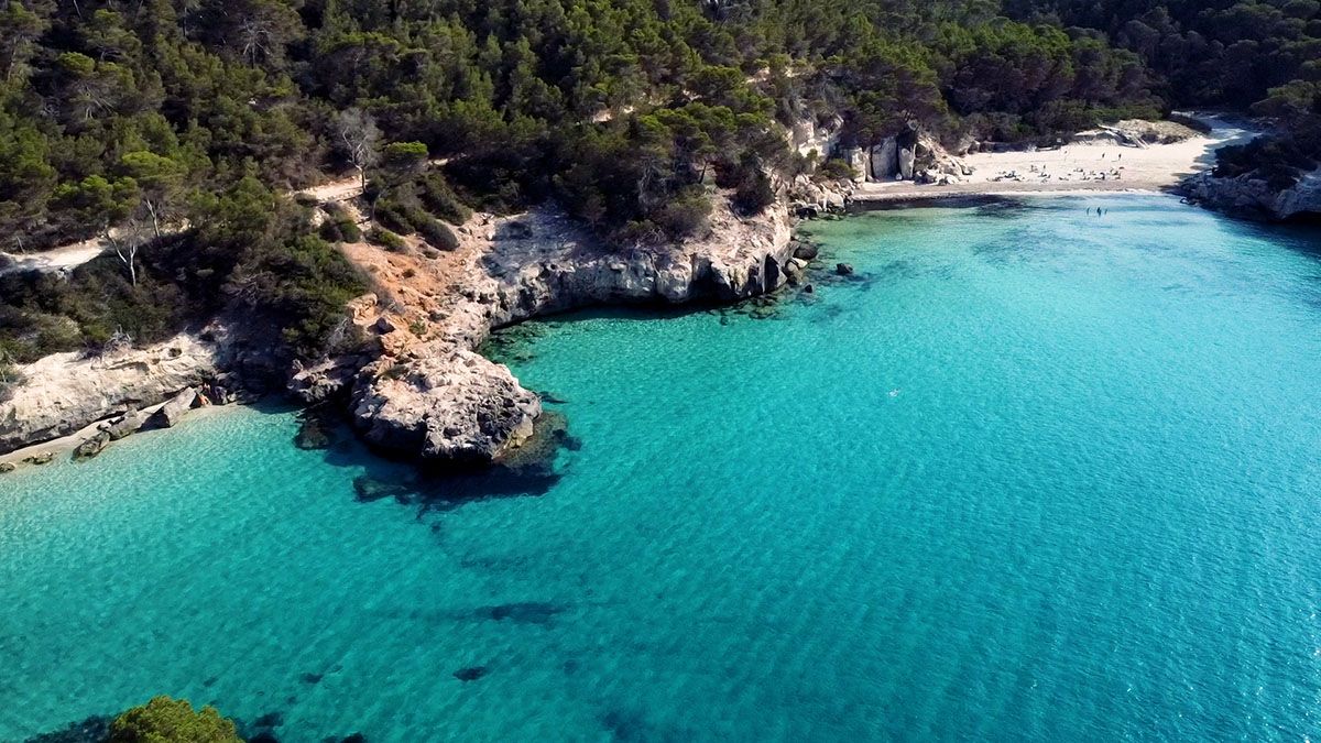 Aguas turquesas y acantilados blancos en una de las calas vírgenes del entorno de Ferreries, puerta de entrada a algunos de los paisajes más salvajes de Menorca