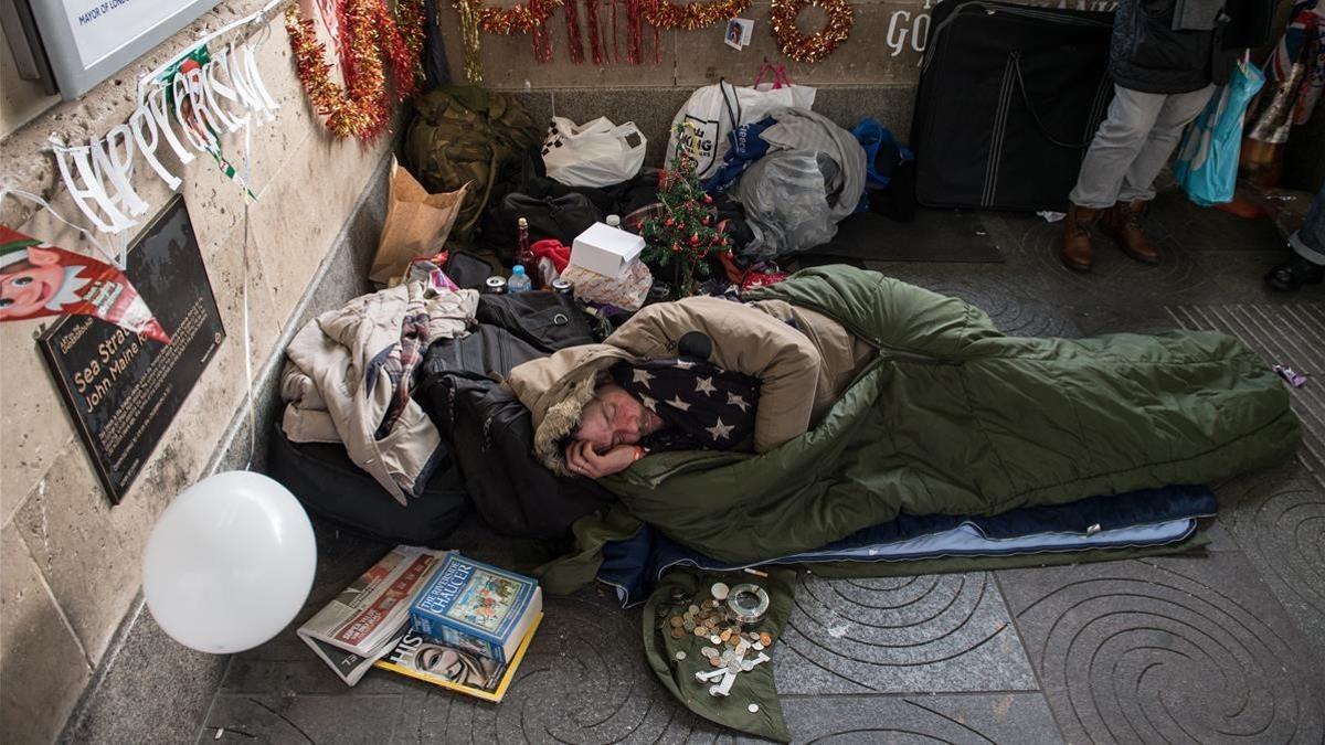 Un sintecho rodeado de motivos navideños que él mismo y un amigo colocaron en el exterior de la estación de metro de Green Park, el 16 de diciembre, en Londres.