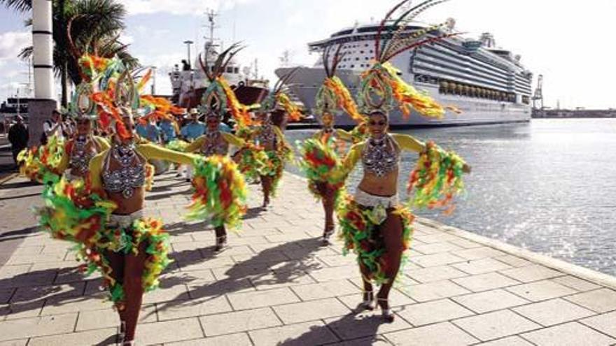 Comparsa en acción con el &#039;Independence of the Seas&#039; al fondo. Debajo, turistas y batucada.