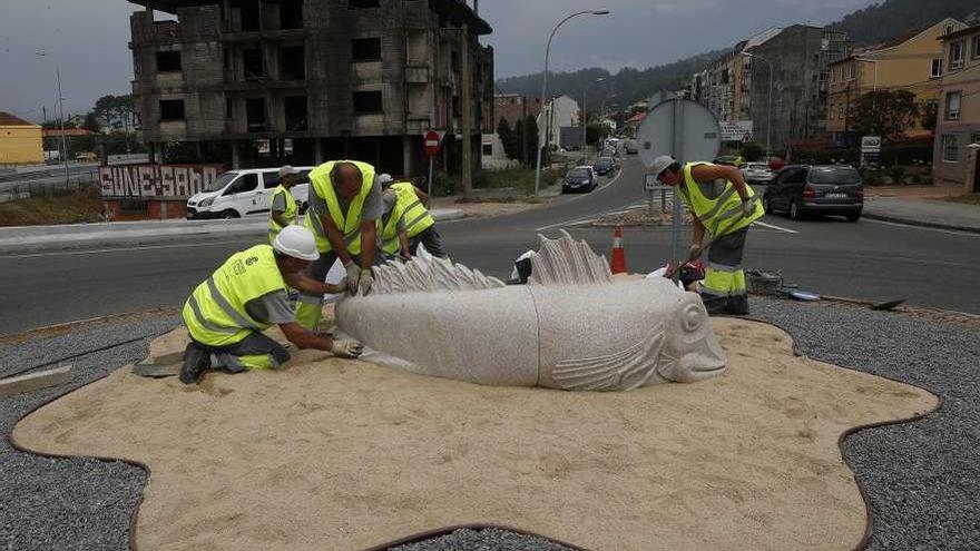 Los operarios instalan el berete de piedra, ayer, en la rotonda del acceso a la autopista en Chapela.  // R. Grobas