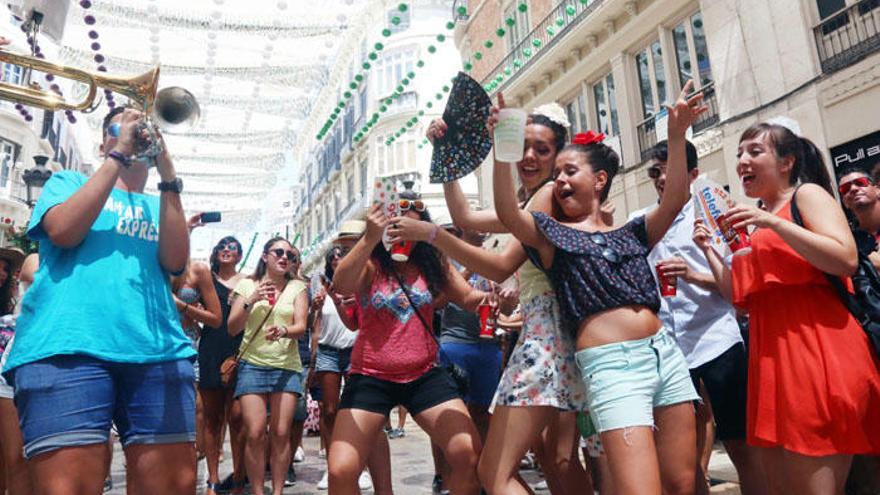 Feriantes en la calle Larios bailando con una charanga.