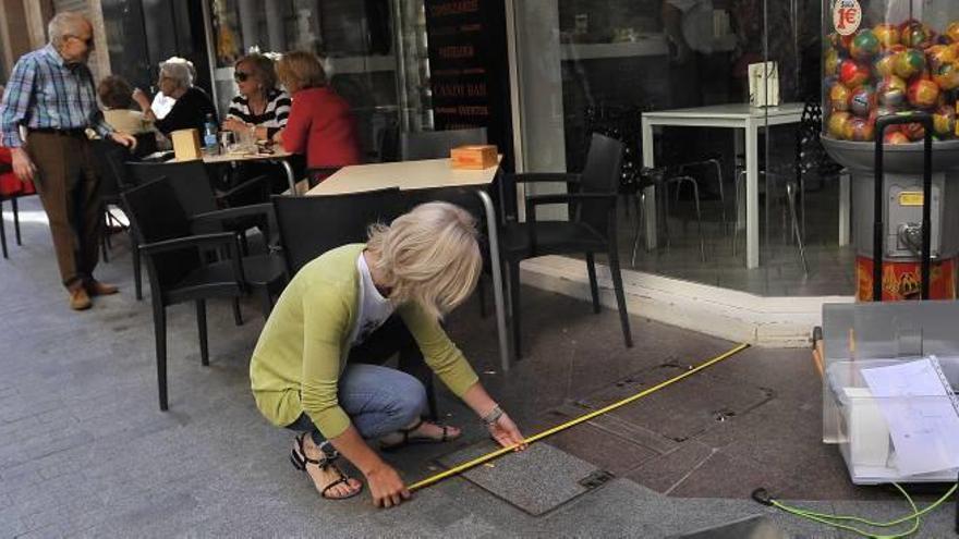 Una técnico de la Concejalía de Aperturas marcando ayer con pintura verde una de las primeras terrazas del centro de Elche.