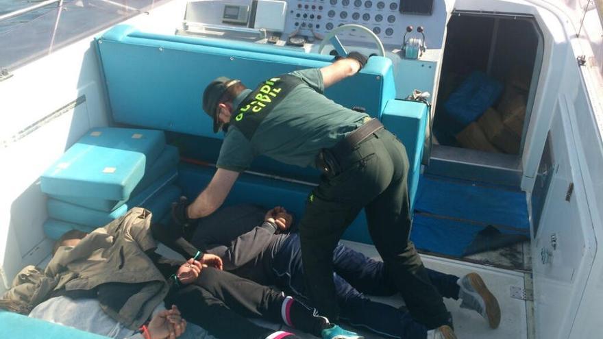 Un guardia civil sostiene a uno de los detenidos en el barco de recreo donde portaban la droga.