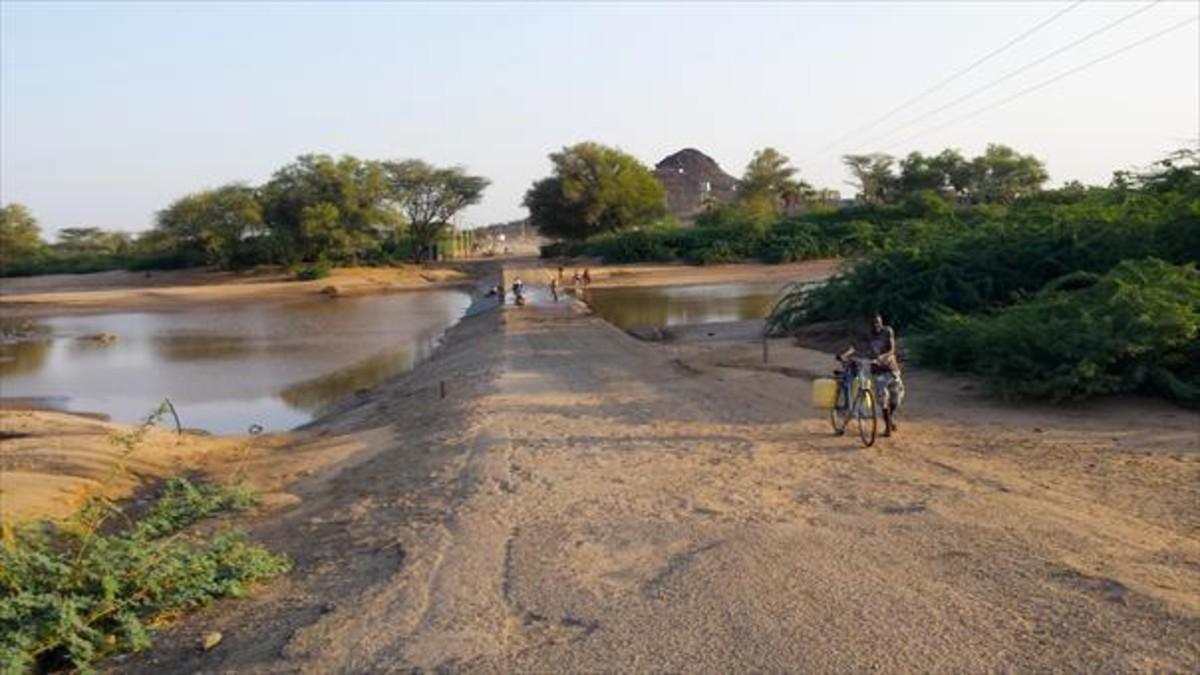 Un hombre regresa con dos bidones llenos después de ir al río a coger agua con su bicicleta en Lodwar, en Kenia. 