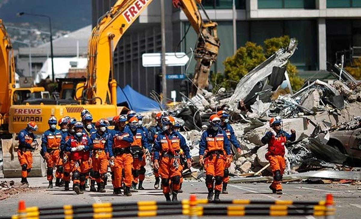 A Christchurch, un equip de rescat japonès camina davant de les ruïnes provocades pel terratrèmol de dijous passat a Nova Zelanda. Les patrulles internacionals de rescat han intensificat la recerca de supervivents, malgrat que cada vegada són menors les esperances de trobar gent amb vida.