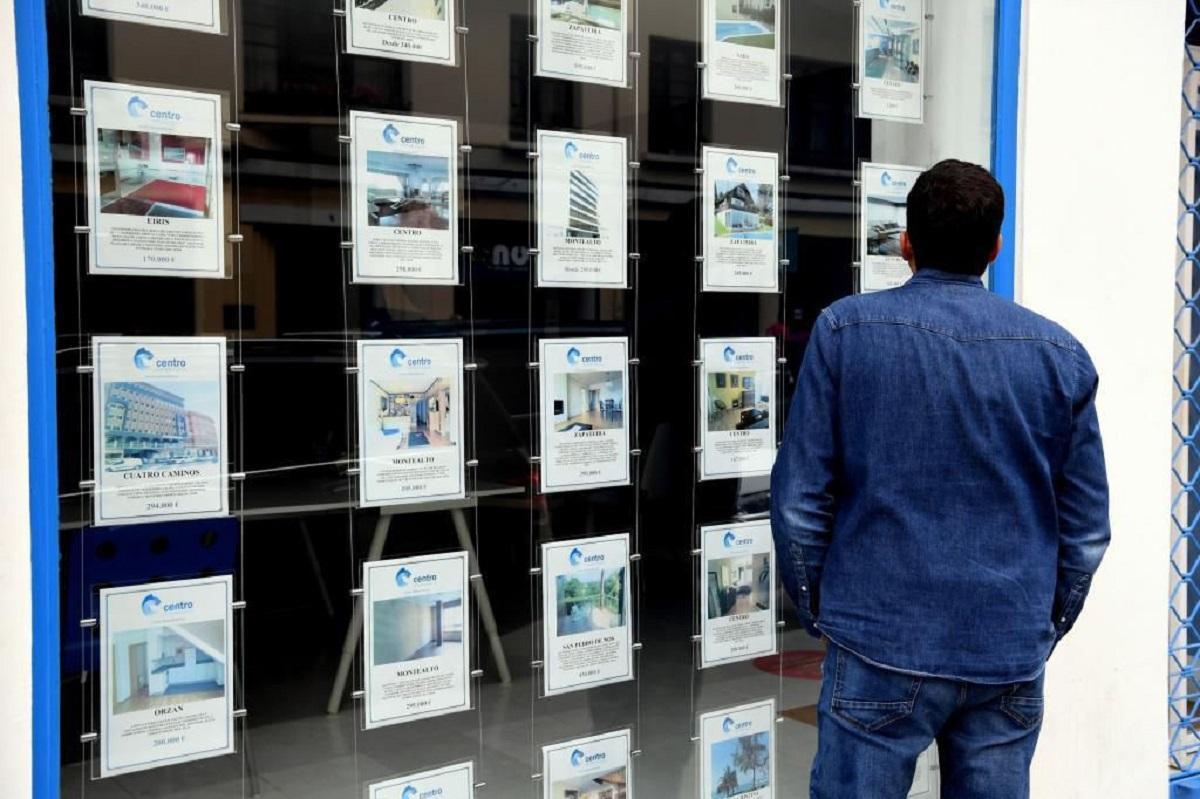 Un hombre observa ofertas de venta de pisos en una inmobiliaria.