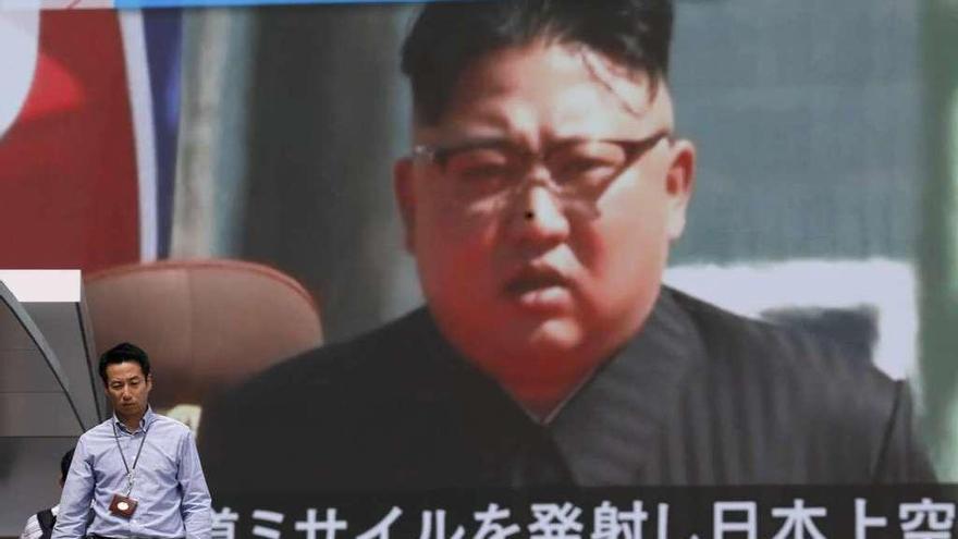 Un peatón camina por una calle de Tokio bajo un monitor gigante con una imagen de Kim Jong-un. // Efe