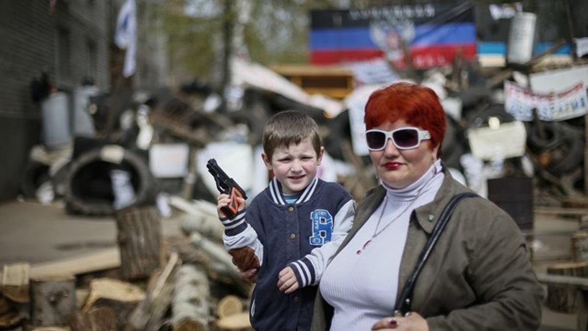 Un niño con una pistola de juguete y una mujer posan ante una barricada en la localidad ucraniana de Slaviansk, este jueves.