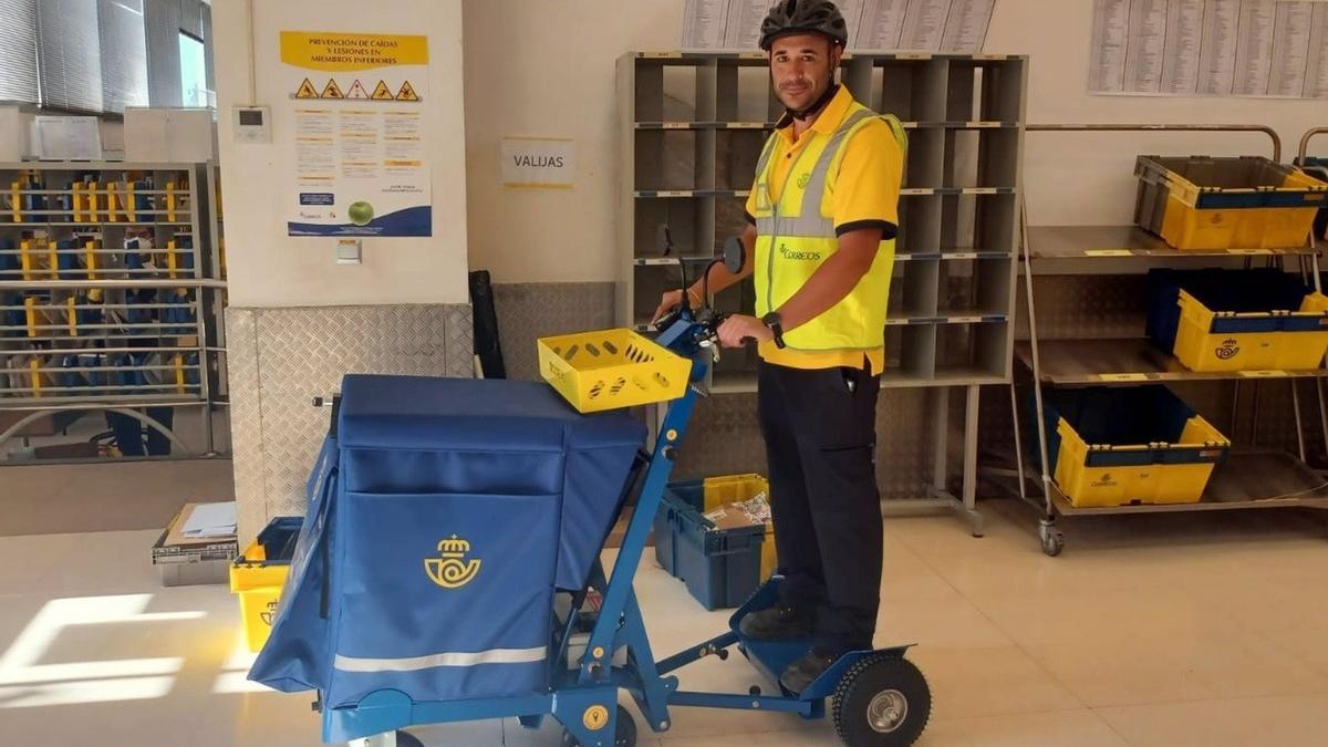 Un repartidor de Correos en una oficina con el carrito asistido que comenzarán a usar.