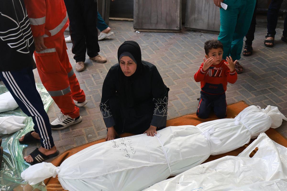 Un niño se sienta junto a una mujer palestina mientras intentaba encontrar el cuerpo de un miembro de su familia muerto en los ataques israelíes en Rafah, en el sur de la Franja de Gaza, en el hospital de al-Najjar el 1 de diciembre de 2023, después de que se reanudaran las batallas entre Israel y el Movimiento Hamás.