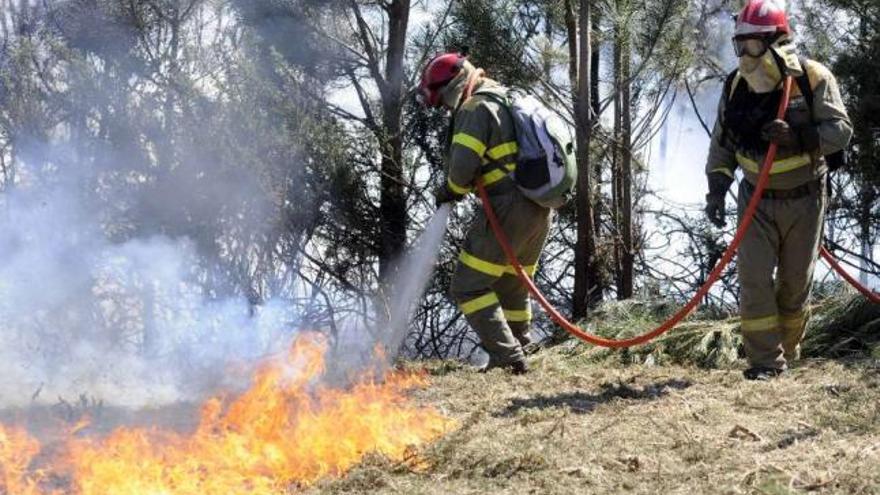 Agentes forestales trabajan en la extinción de un incendio el verano pasado en un monte gallego. / noe parga