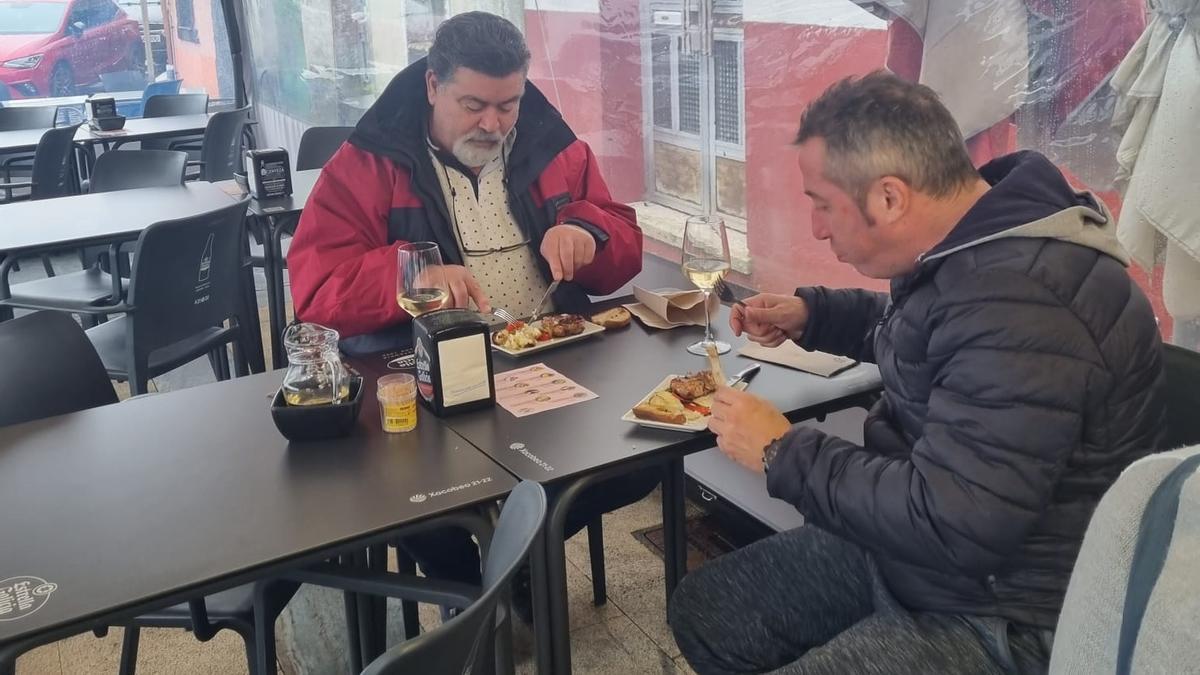 Dos clientes saborean el pincho ofrecido en el bar O Choco, uno de los locales de Pontecesures que participan en la ruta de tapas con productos de la tradicional matanza del cerdo.