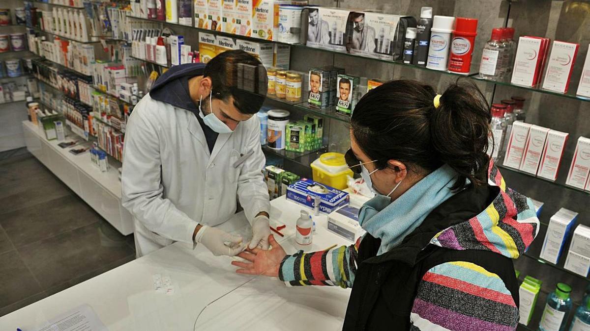 Un farmacéutico realiza una prueba serológica en una farmacia de Orense, en Galicia.