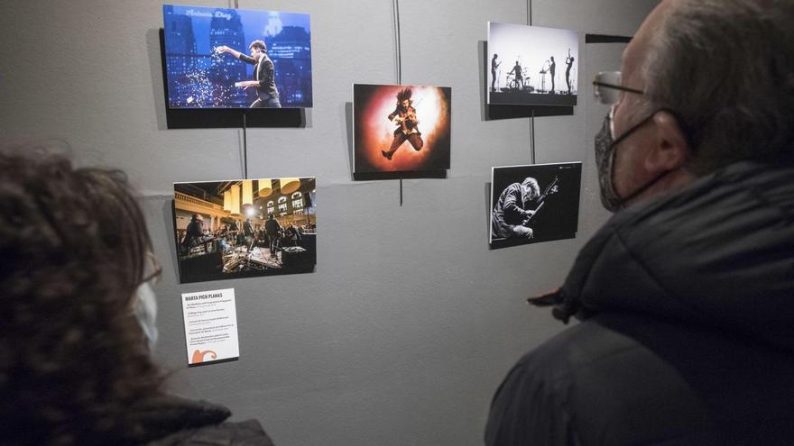 Dos espectadors miren les fotografies de Marta Pich que s’exposen a la Plana de l’Om juntament amb les de catorze autors més