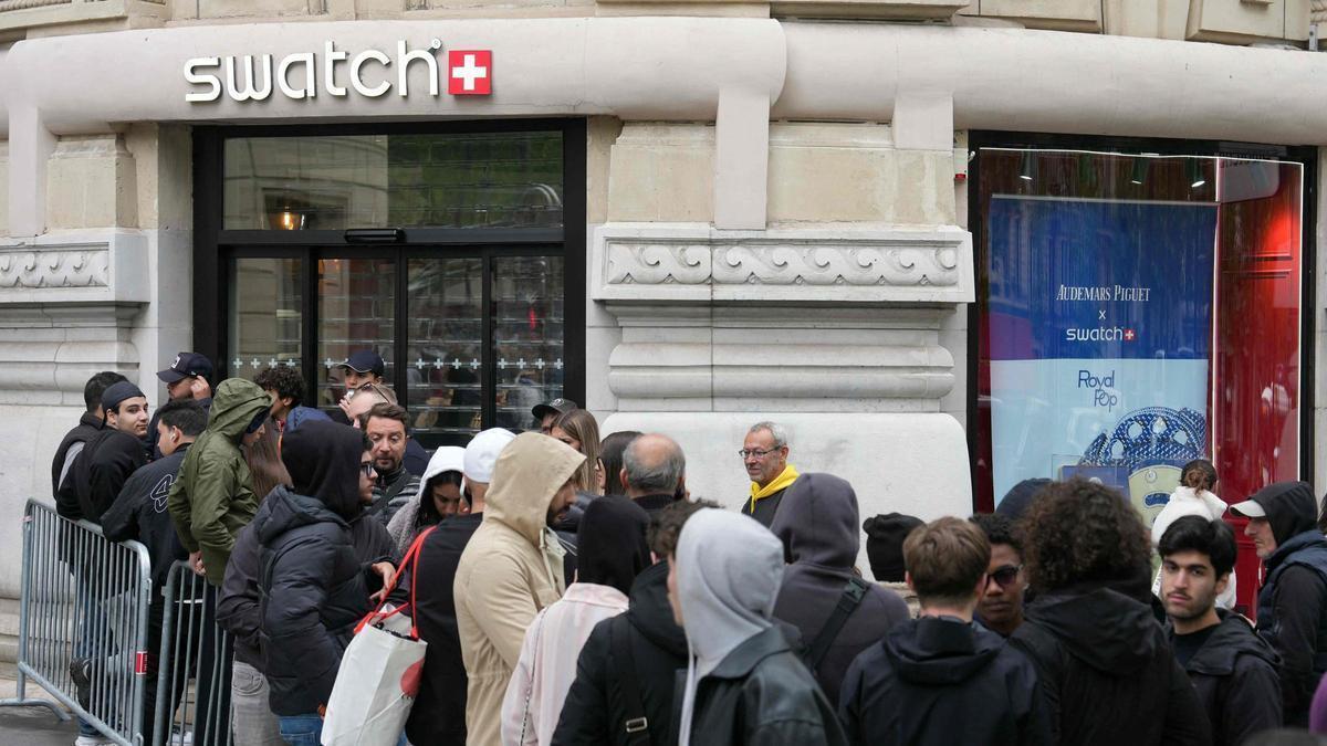 Clientes haciendo cola frente a una tienda cerrada de la marca suiza de relojes Swatch en París, en el marco de una campaña promocional de sus relojes Royal Pop.