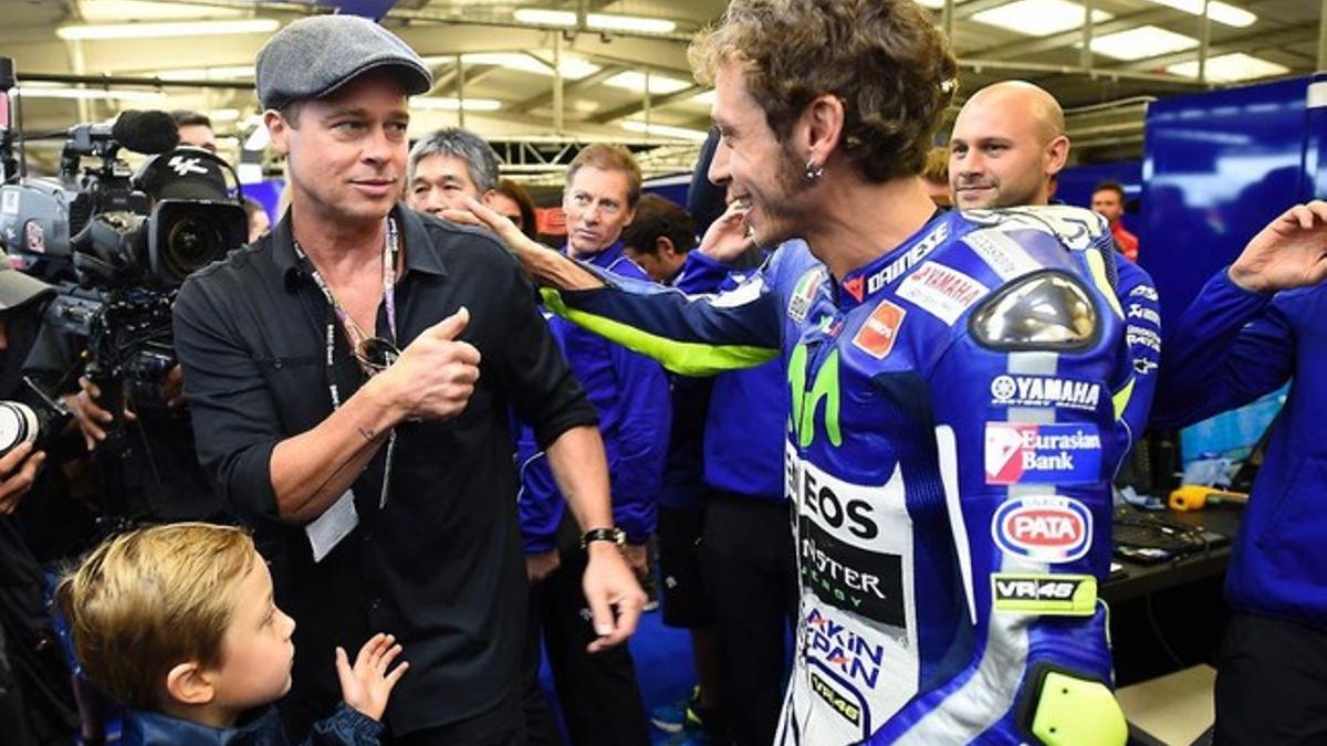 Brad Pitt, acompañado por su hijo Knox, saluda a Valentino Rossi en el circuito de Silverstone.