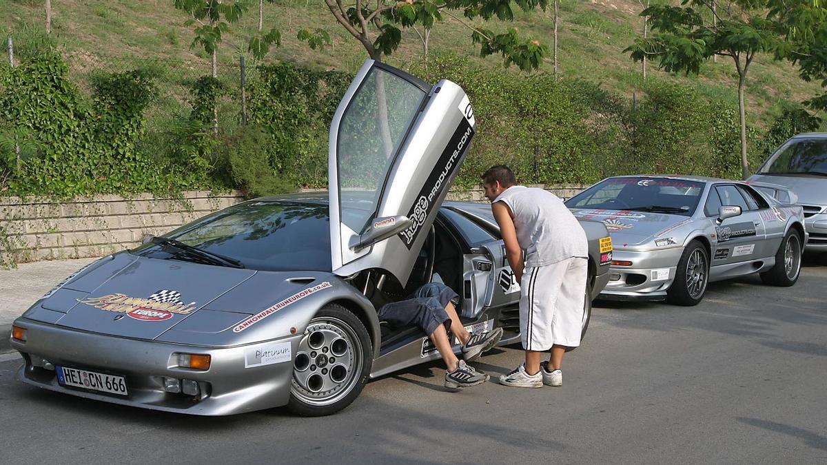 GRANOLLERS 20040913 DETENIDOS LOS PARTICIPANTES DE LA CARRERA ILEGAL CANNONBALL RUN EUROPE PRESTAN DECLARACION EN LA COMISARIA DE LOS MOSSOS D'ESQUADRA DE GRANOLLERS EN LA FOTO UN PILOTO DETENIDO LE ENSEÑA EL VEHICULO A UN JOVEN AFICIONADO FOTOGRAFIA DIGITAL DE JOSEP GARCIA