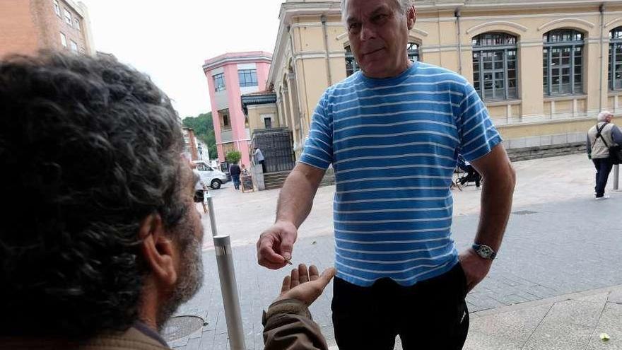 Manuel Gómez da una moneda a un mendigo, en el centro de Mieres.