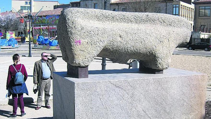 Turistas admiran el toro de piedra que ha sido objeto de una pintada.