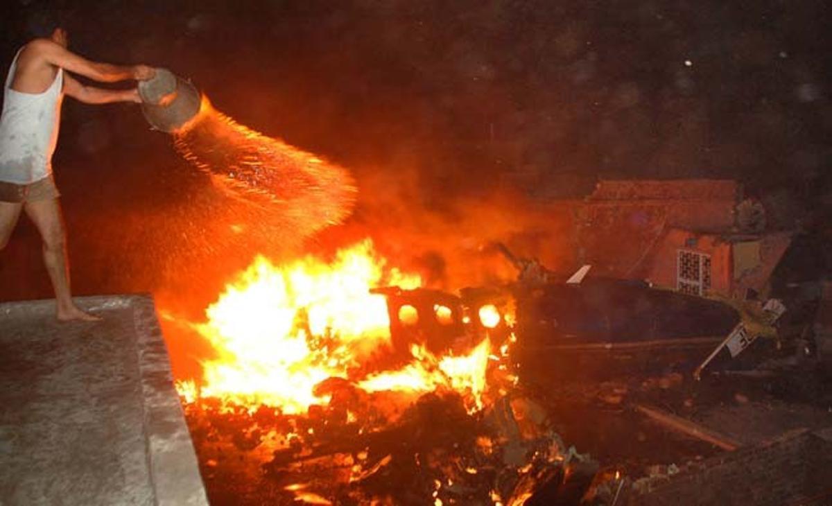Un veí del barri de Faribad combat el foc provocat per l’avió que s’ha estavellat en aquest suburbi de Nova Delhi (Índia) i ha provocat 10 morts.