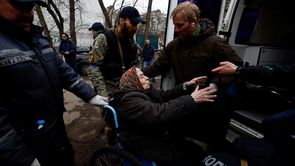 Los voluntarios ayudan a Larysa Kolesnyk, de 82 años, a salir de la camioneta después de que fue evacuada de la ciudad de Irpin, mientras continúa el ataque de Rusia a Ucrania