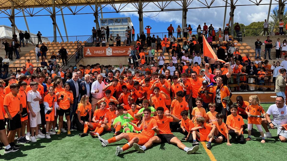 Jugadores, entrenadores, aficionados y directivos celebran el ascenso del Platges de Calvià juvenil a Honor en el campo de Magaluf.