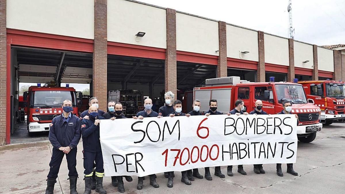 Els Bombers de Girona ahir amb la pancarta de protesta durant la visita del conseller.