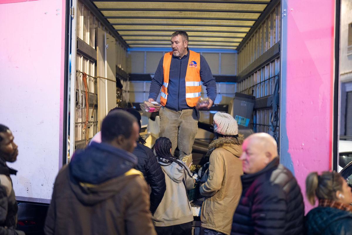 Voluntarios de distintas entidades privadas reparten comida para la cena de Nochebuena bajo la autopista C-31, donde aún duermen decenas de personas desalojadas del antiguo instituto B9