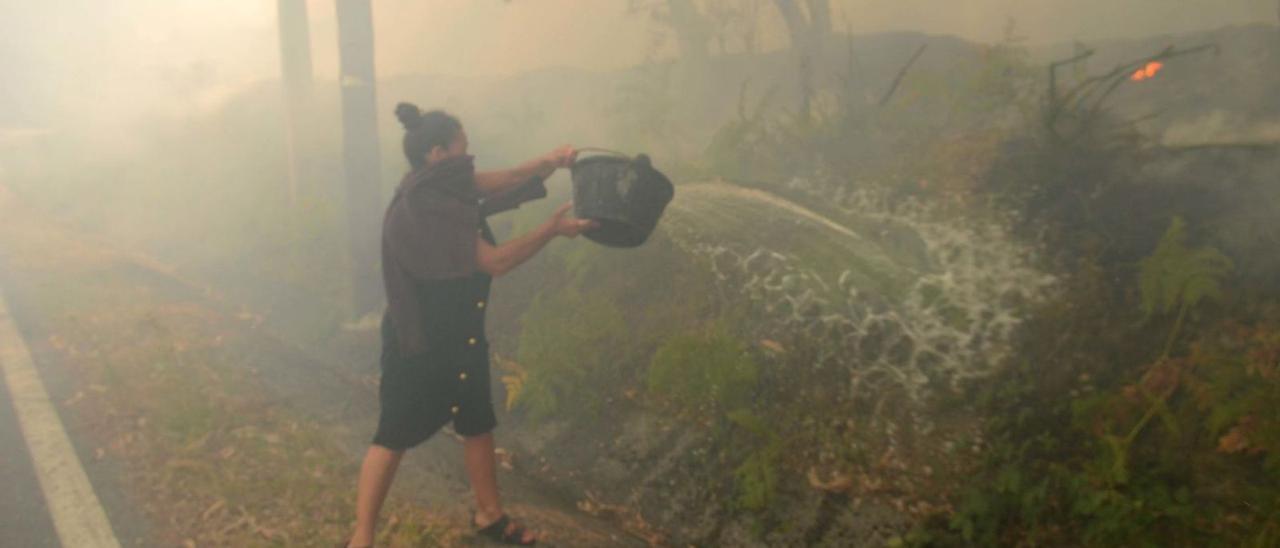 Una mujer lucha contra las llamas durante el incendio registrado en Xiabre.