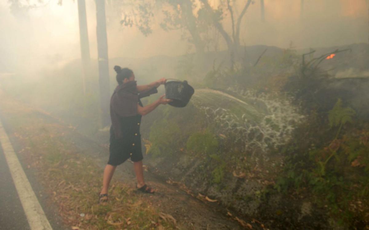 Una mujer lucha contra las llamas durante el incendio registrado en Xiabre.