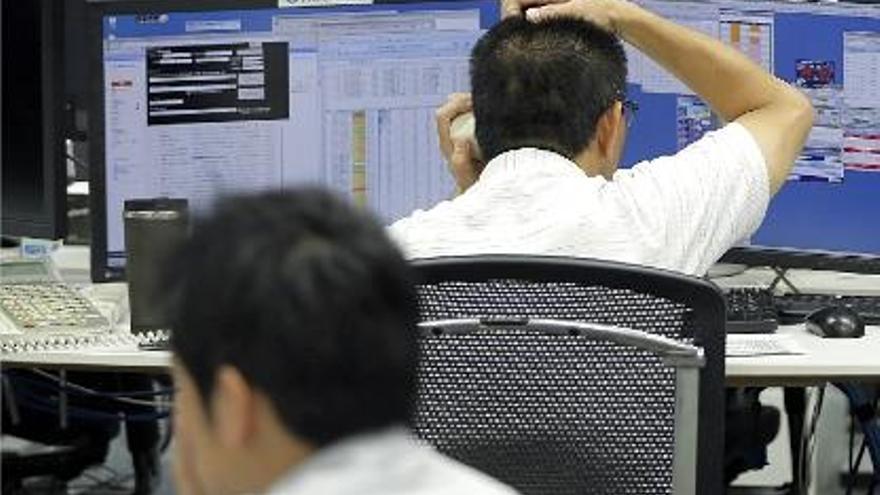 Brokers japonesos en plena activitat consultant cotitzacions en una pantalla.
