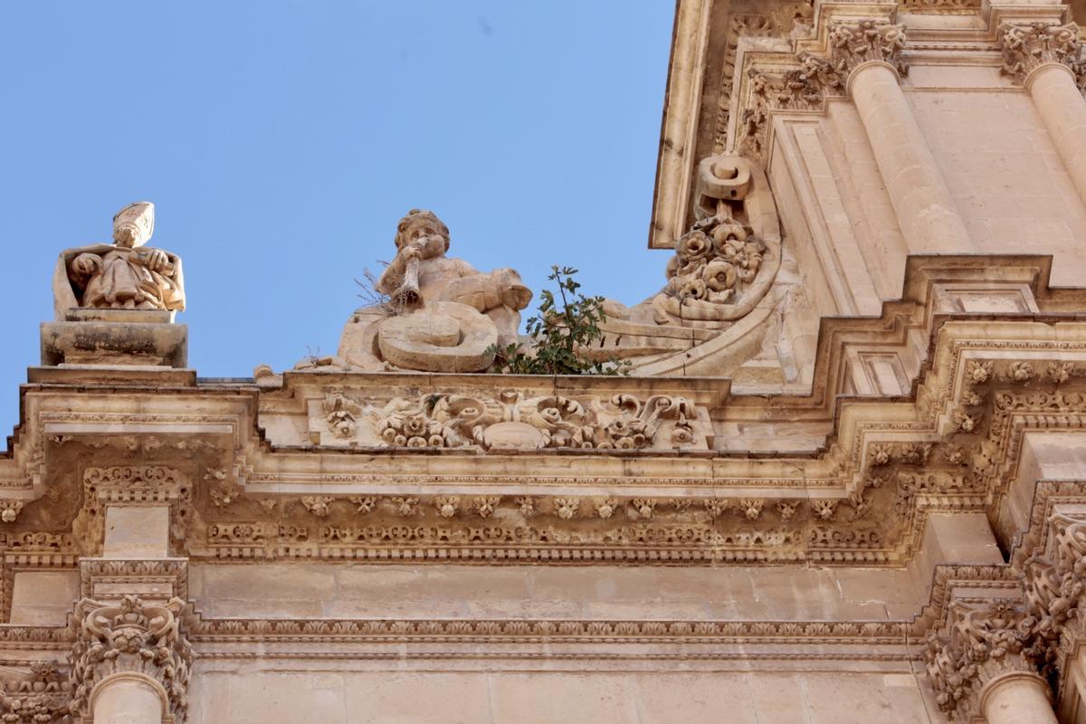 Arbustos y una higuera junto a uno de los ángeles del lado izquierdo del tercer cuerpo de la fachada de la antigua colegial de San Patricio.