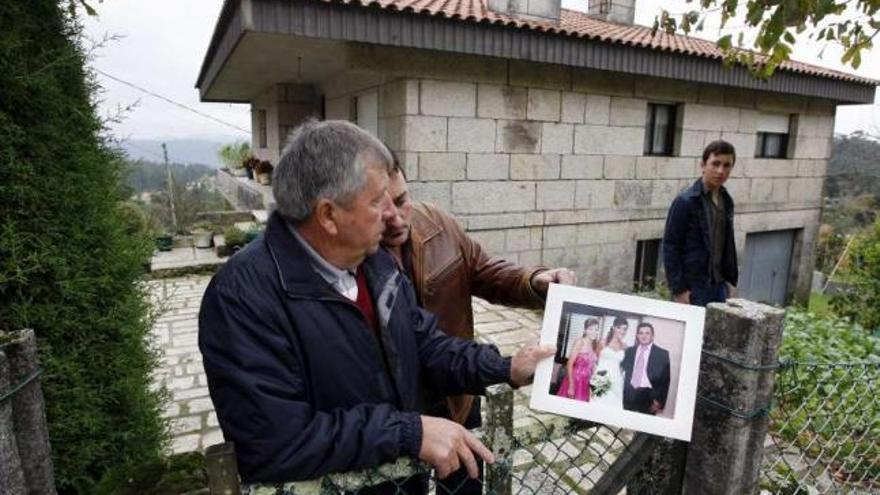 El padre y el hermano de la víctima mostrando una foto de María Isabel en una boda. / marta g.brea