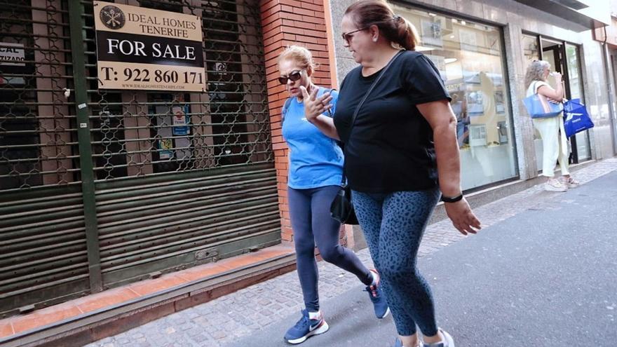 Dos personas pasan por delante de un cartel que oferta casas en Santa Cruz de Tenerife. | | MARÍA PISACA