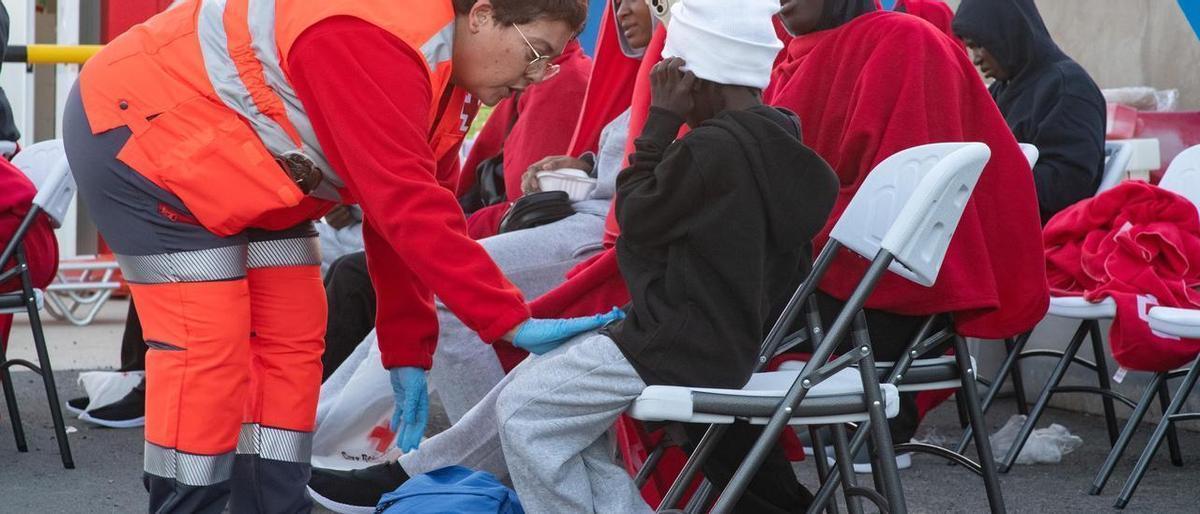 Una voluntaria de Cruz Roja atiende a una niña en recién llegada a Fuerteventura.69 personas en dos neumáticas a al sur de Canarias, entre ellas tres niños.