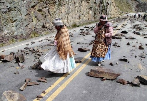 Women walk on a road blockaded by independent miners in the La Cumbre mountain pass near La Paz